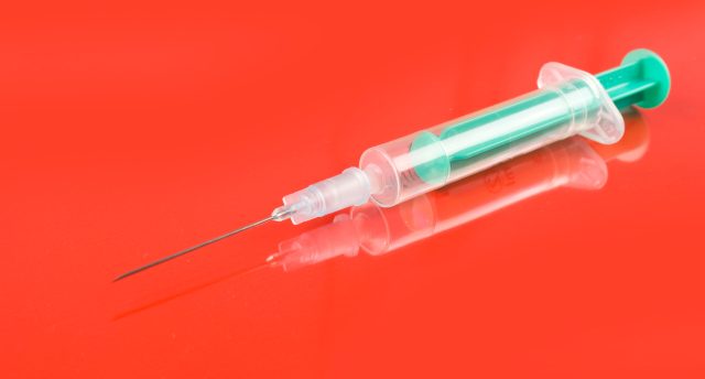 photo of Medical Syringe on red background