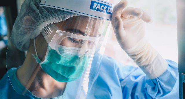 Nurse having headache from work while wearing PPE suit for prote